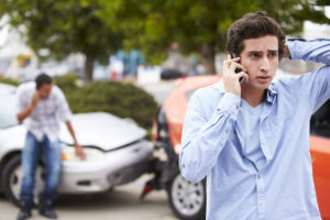 Teen driver calling his parents after car accident.