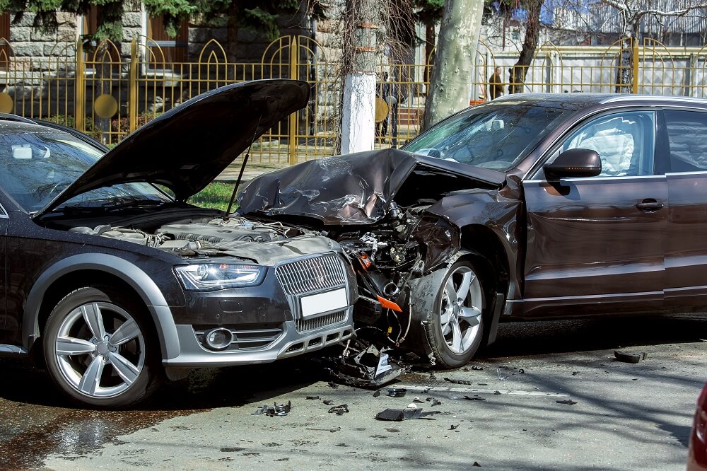 Two sedan cars in head-on collision accident happening at the intersection.