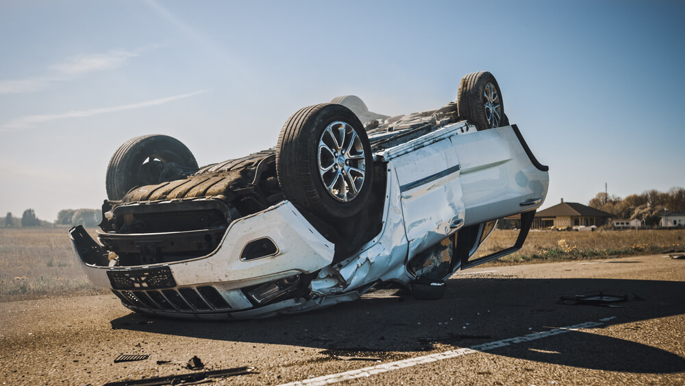 An overturn car lying upside down on a street after an accident.