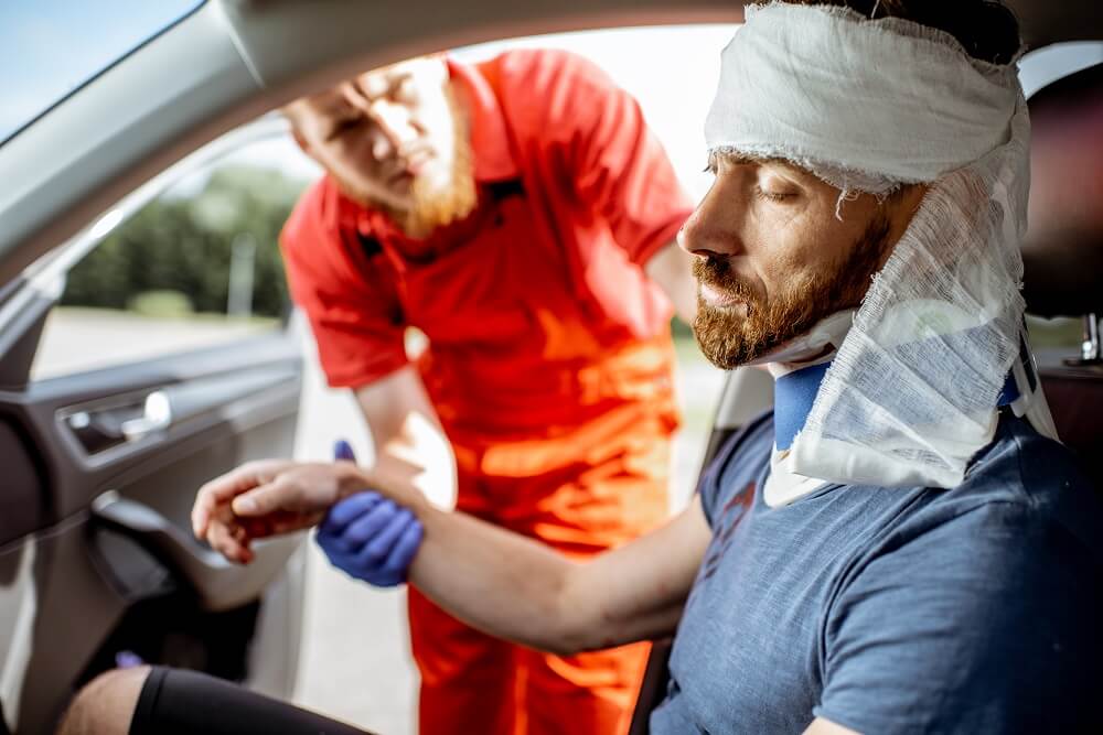 Paramedics rescuing injured driver from car accident.