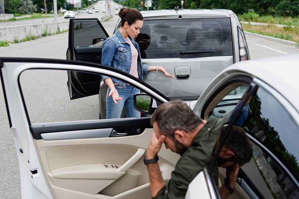 Female driver checking damages after car accident.