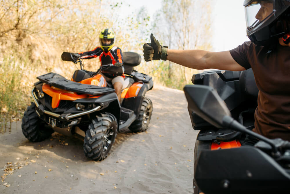 ATV rider showing thumbs up to his partner.